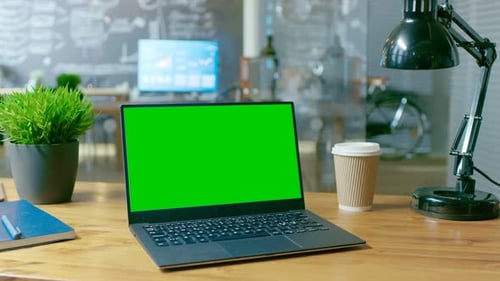 Personal Computer with Mock-up Green Screen Monitor Stands on the Office Desk. In the Background St