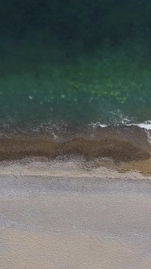 Aerial Vertical View of Beach with Wave Caressing Shore Sun Glare Small Waves on the Water Surface