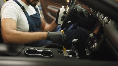Mechanic Detailing Car Interior with Brush and Solution