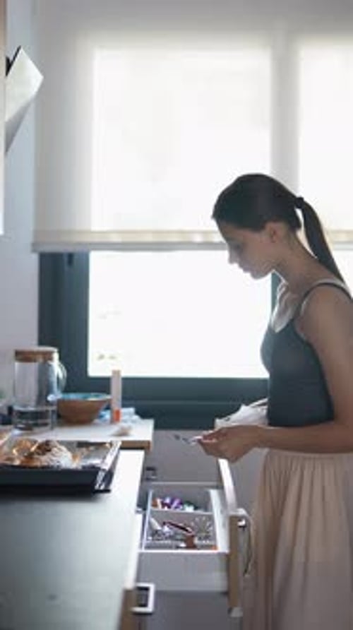 Young Woman Cleaning a Spoon in Kitchen
