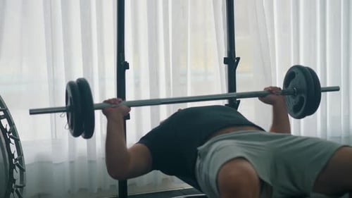 Mann macht schweres Bankdrücktraining mit einer Langhantel im Fitnessstudio