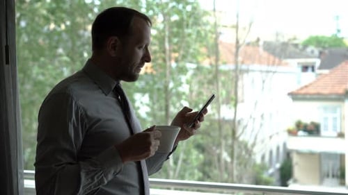 Man uses phone drinks coffee indoors in daytime