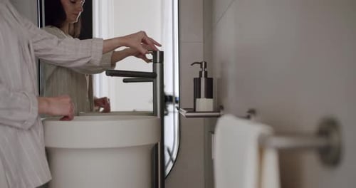 Woman Washing Hands in Modern Bathroom Sink
