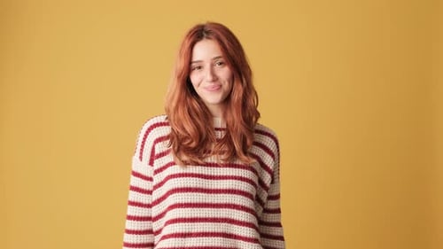 Smiling girl showing double thumbs up in studio on yellow background