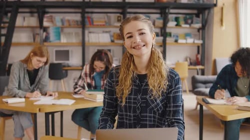 Smiling Young Woman Studies with Laptop in Library