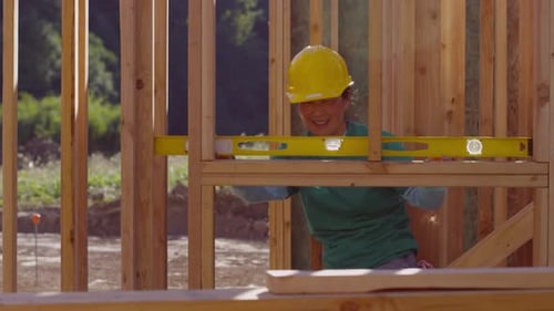 Volunteers construct wooden building frame with level