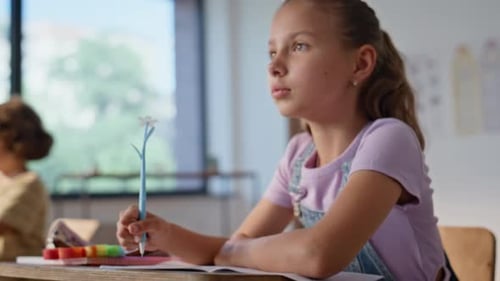Girl Writing at Desk in Classroom