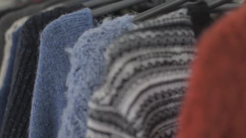 Clothes and stuff in boutique store. Focus change on the orange sweater. Camera panning from left to