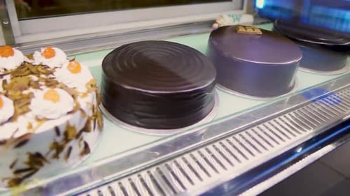 A moving shot of several types of cakes at a display window in a bakery