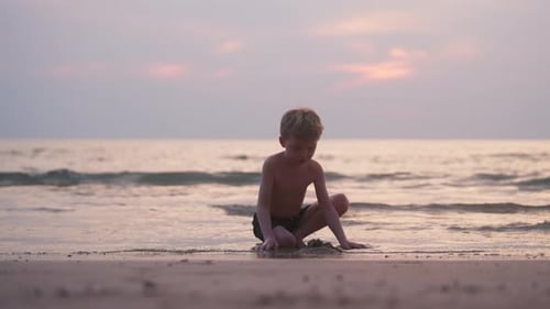 Young Child Plays on the Beach at Sunset