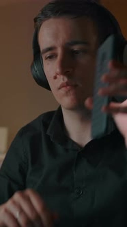 Young Adult Uses Phone and Laptop with Headphones