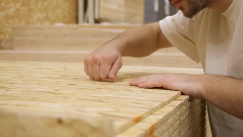Customer Inspects Board Texture Closely in Building Supply Section Arm Stretches Forward Feeling