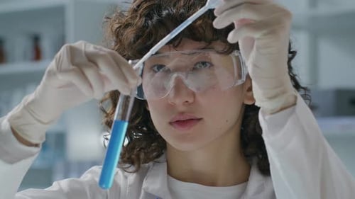 Woman Scientist Pipetting Liquid into Test Tube in Lab