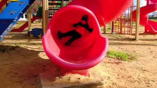 Happy Preschooler Boy Plays on Playground Slide Cool Sunny Day
