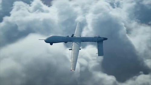 Military Drone Flying Above Clouds and Landscape
