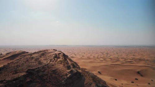 Die Drohne fliegt an einem klaren Tag mit Blu an einer Sanddüne vorbei in Richtung Horizont in der Wüste vor Dubai