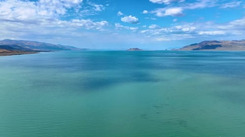 The beautiful azure of the waterscape and sky reflecting in it. Fluffy clouds hang over the scenery
