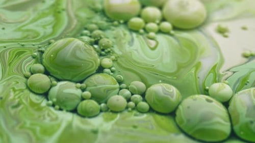 Bubbles filled with green paint slowly moving in liquid