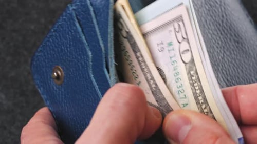 A Closeup View of Cash Being Stored in a Blue Wallet for Financial Purposes