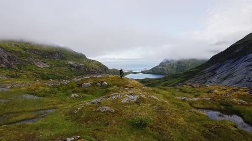 Tourist with a Backpack on Top and Looking at the Landscape on the Way to the Top of Manken Mountain