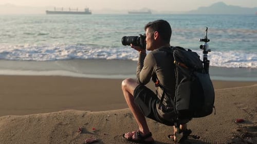Travel photographer at the beach takes a landscape photo on his DSLR professional camera with a back