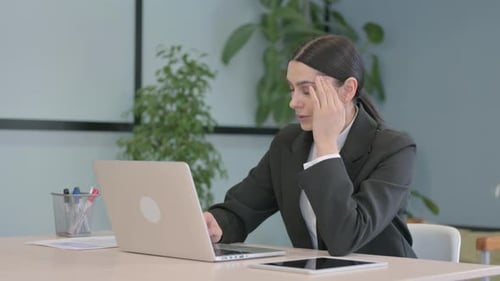 Businesswoman with Headache at Desk Using Laptop