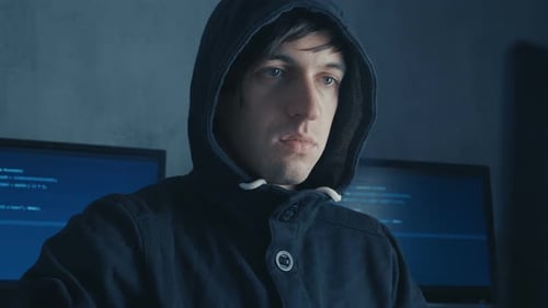 Man in Hood Sitting at Table and Coding on Laptop