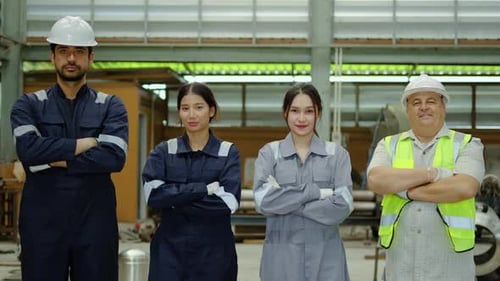 Diverse team of confident industrial factory workers standing together with crossed arms and smiling