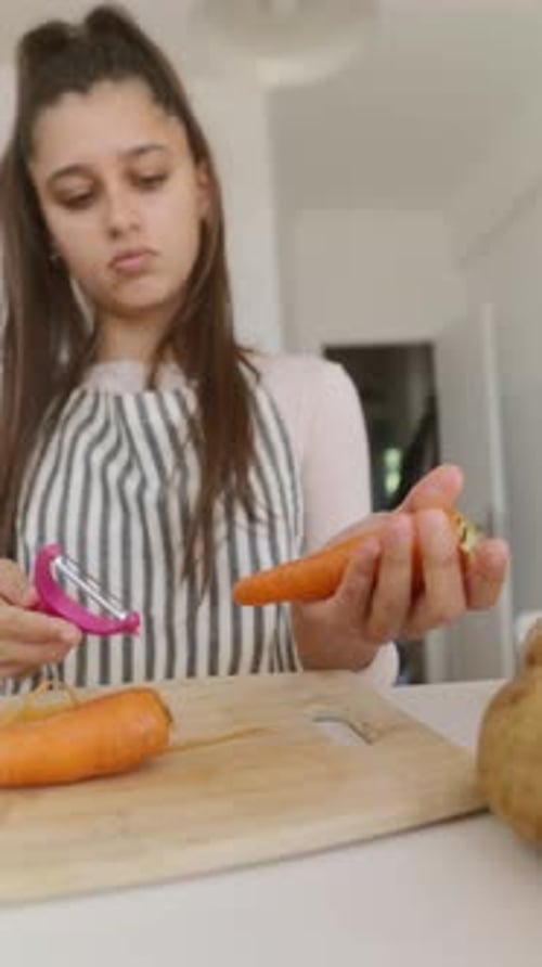 Young Woman Peeling Carrot in Kitchen