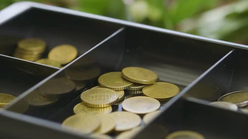Close-up of a hand taking coins out of a cash register drawer