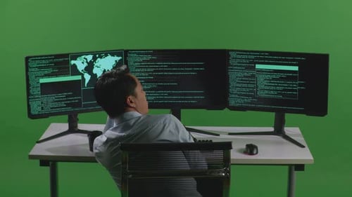 Back View Of Bored Asian Man Developer Write Code With Multiple Computer Screens In Green Screen
