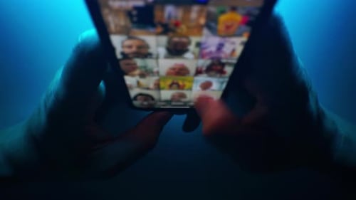 Hands Scroll Through Images on a Smartphone at Night
