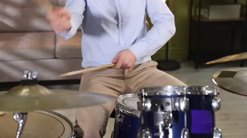 Man playing drums with drumsticks in studio, closeup