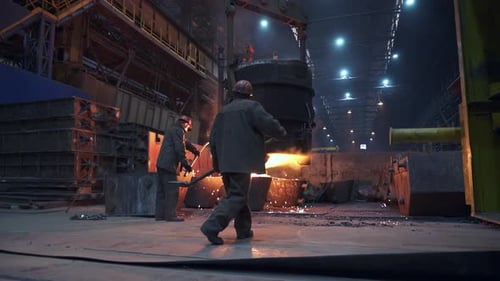 A Dedicated Worker is Pouring Molten Metal Into a Mold in an Industrial Foundry Stock Clip