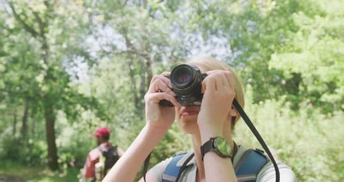 Couple heureux et diversifié avec des sacs à dos prenant des photos dans le parc, Ralenti