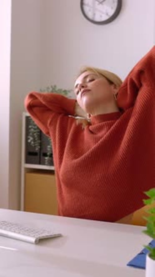 Attractive Young Businesswoman Stretching Arms Sitting in the Office
