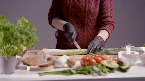 Woman Cutting Leek with Vegetables on Table