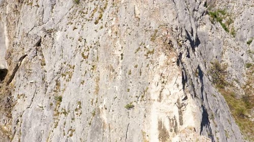 Flying through vertical limestone walls in a deep gorge, canyon, rock climbing aerial
