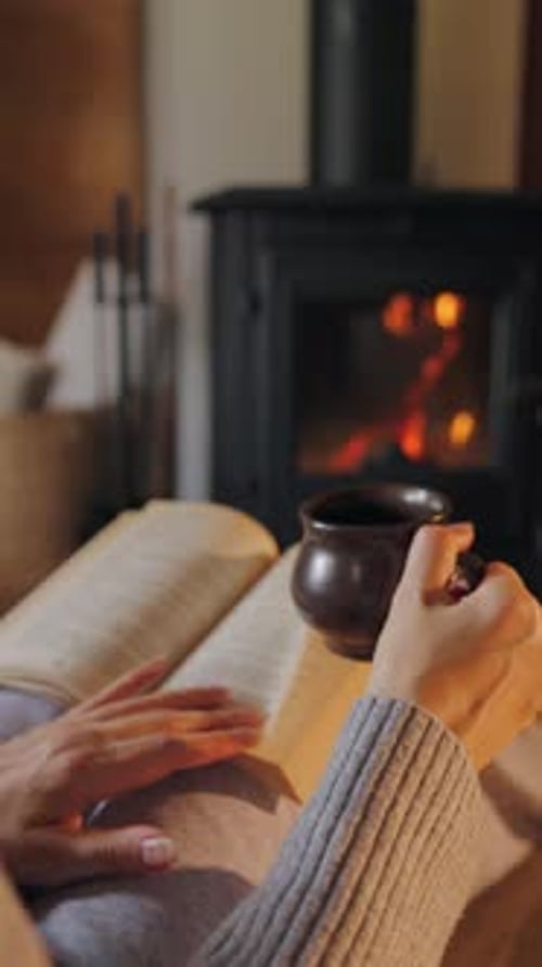 Woman Reading Book with Coffee by Fireplace