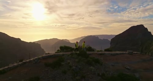 Couple Hiking on Mountain Ridge at Golden Sunrise