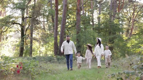 Young mother, father with daughter and sons are walking, having fun in autumn forest. Family holding