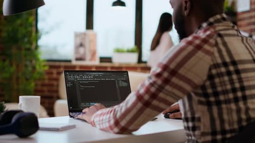 Afroamerikanischer Softwareingenieur arbeitet an Laptop-Eingabecode für ein Projekt