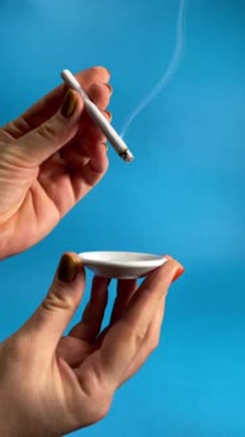 Hands Extinguish a Cigarette in Small Ashtray