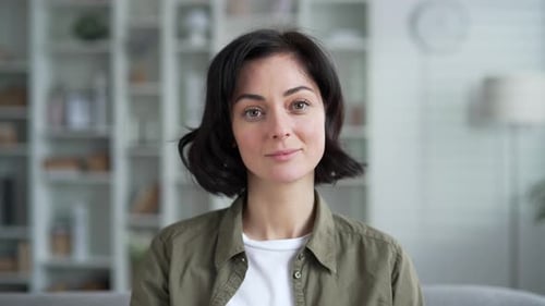 Portrait of a young woman with short dark hair smiling slightly while sitting in modern comfortable