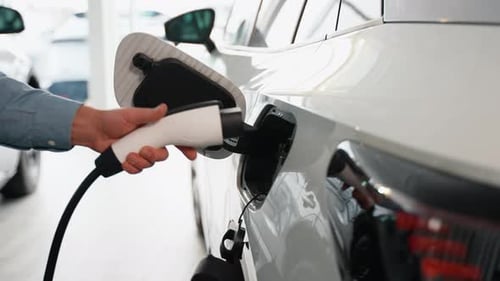 Closeup of Man's Hand Inserting a Charger in Luxury Electric Car in Dealership