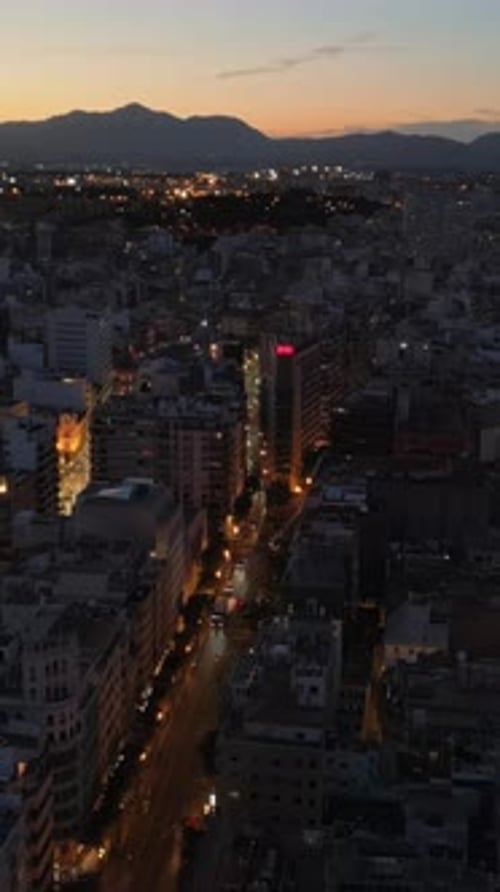 Aerial drone view of cars moving between the buildings in Alicante, Spain in the evening. Vertical