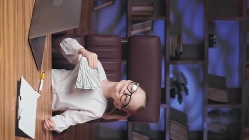 Goldenhaired Girl Fanning Dollar Banknotes in Office