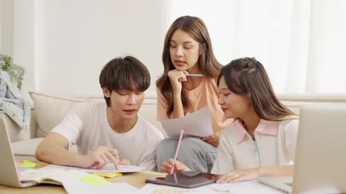 4K Group of Asian college students making project report together in home living room.