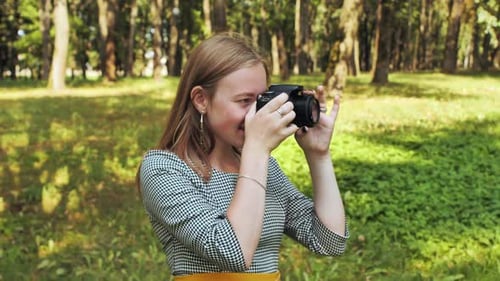 Woman with Camera Taking Pictures in Park
