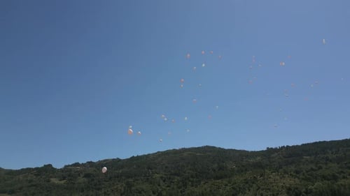Balloons Floating Over a Green Mountain